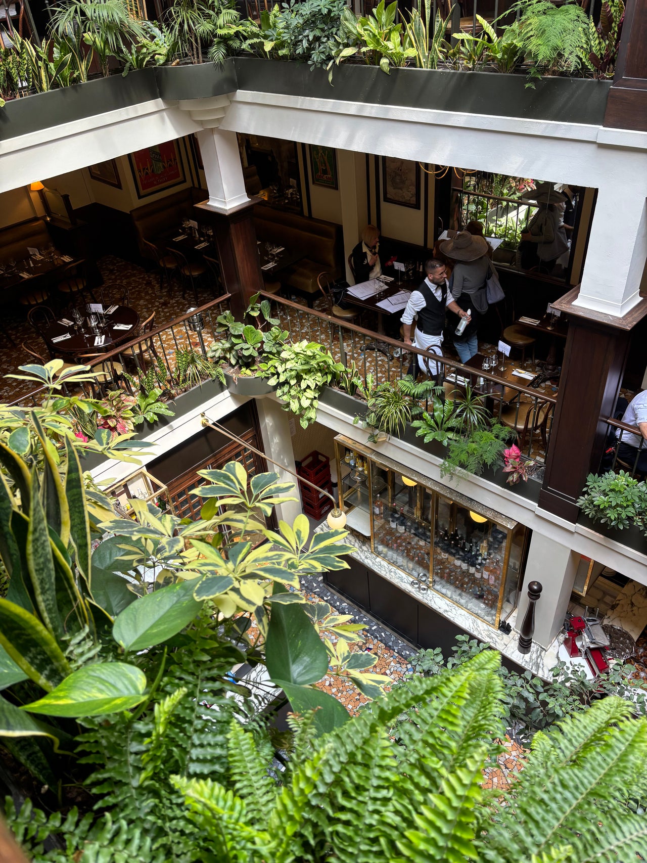 Le Café du Commerce interior with mezzanine dining, leafy decor, and vintage French bistro charm