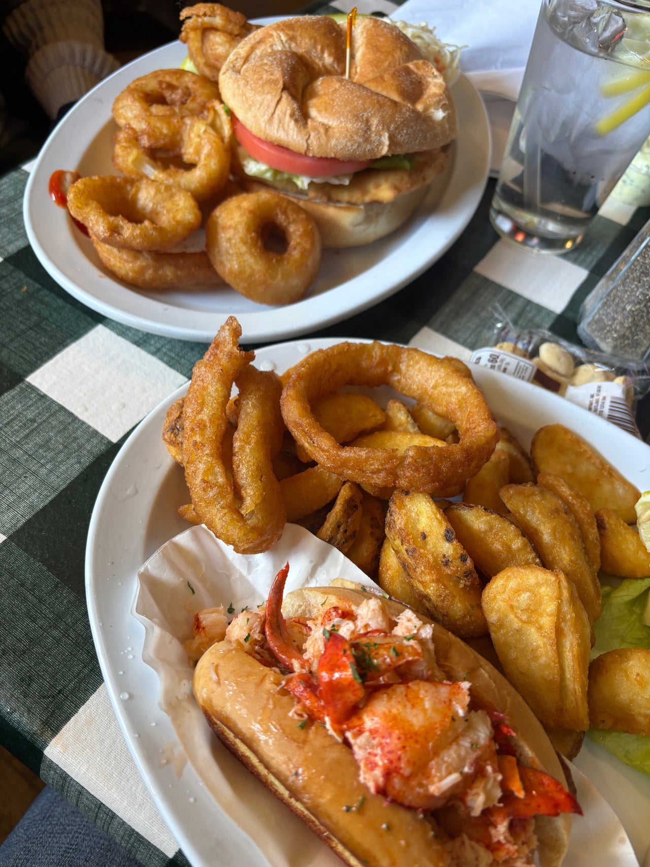 Close-up photo of a lobster roll platter at Seven Seas Pub in Milford, Connecticut, served with fries and onion rings alongside a fish sandwich, capturing a cozy New England seafood pub atmosphere with casual nautical charm.