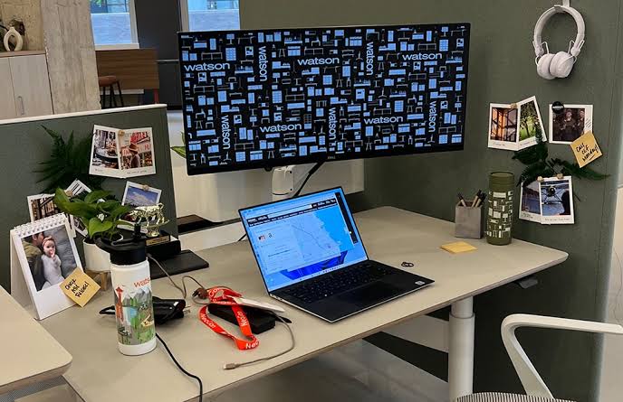  Modern office desk setup featuring an ultra-wide monitor, laptop, and personal workspace decor representing the evolving hybrid remote work environment. 