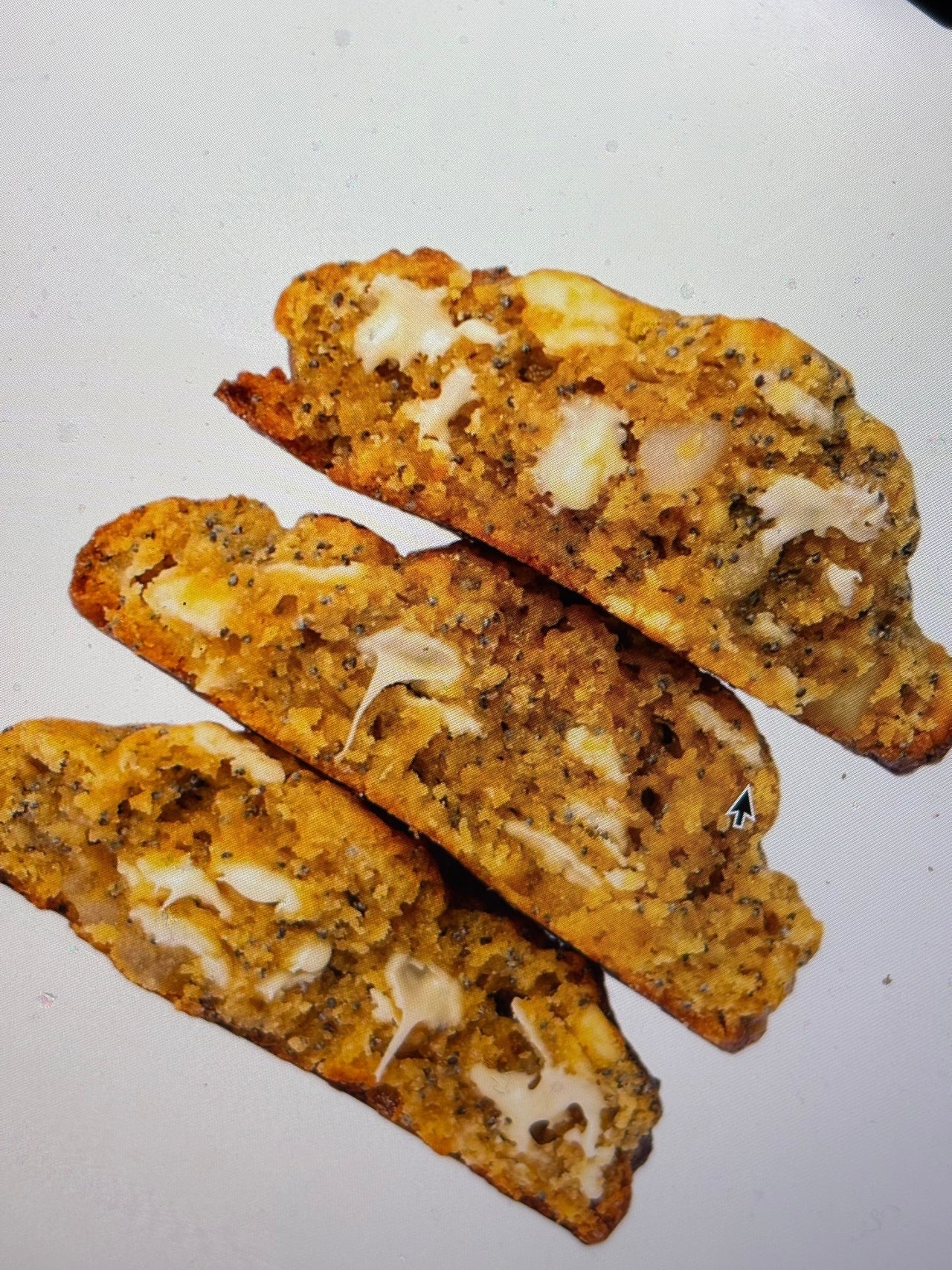Warm lemon poppy seed and white chocolate cookie from Puffy Cookies with a gooey center, fresh out of the oven, photographed in a Paris bakery setting