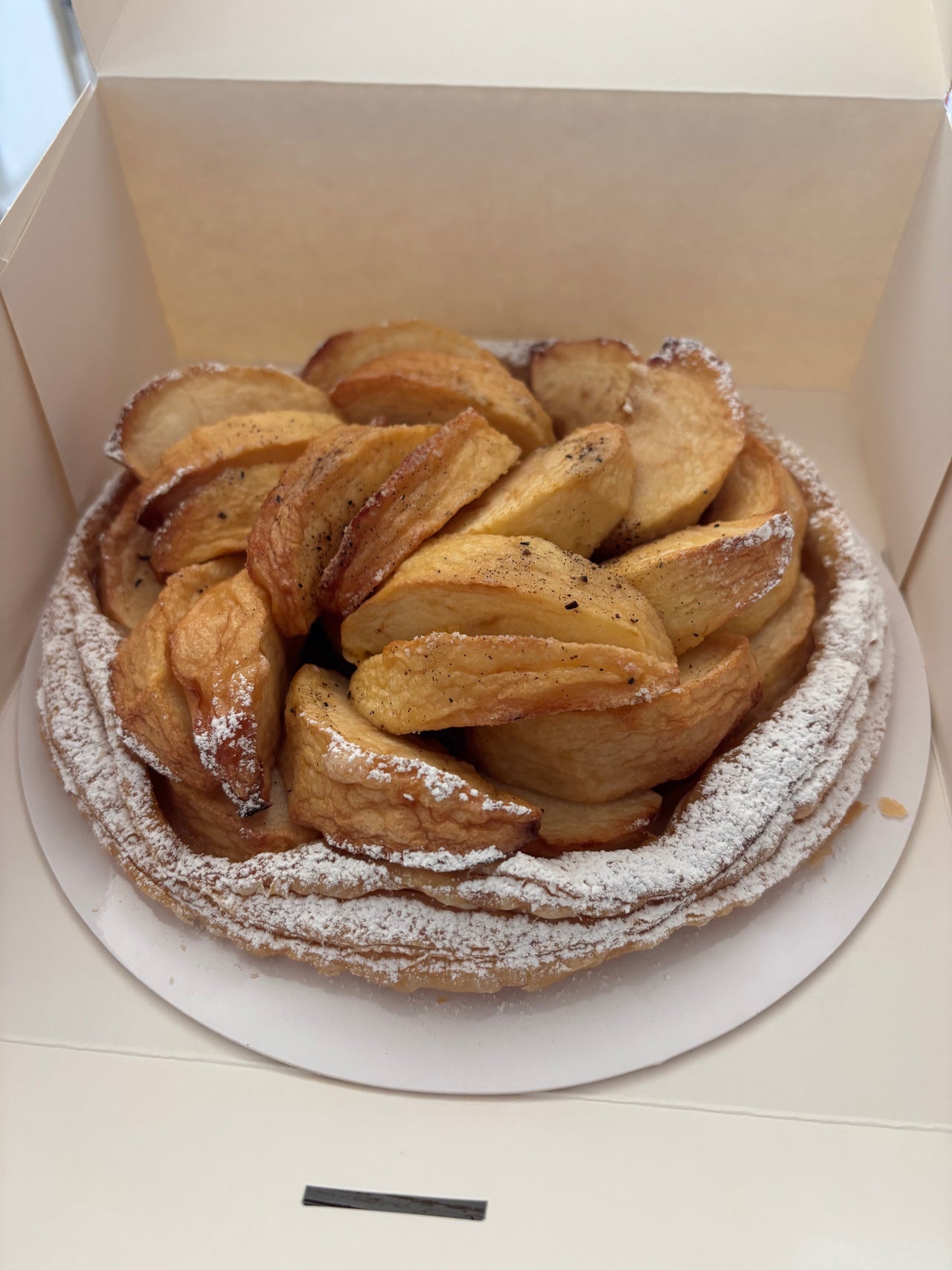 Authentic photo of Lenôtre’s Tarte Éléonore in Paris, featuring golden Chantecler apple slices arranged in a distinctive spiral pattern on a buttery crust.